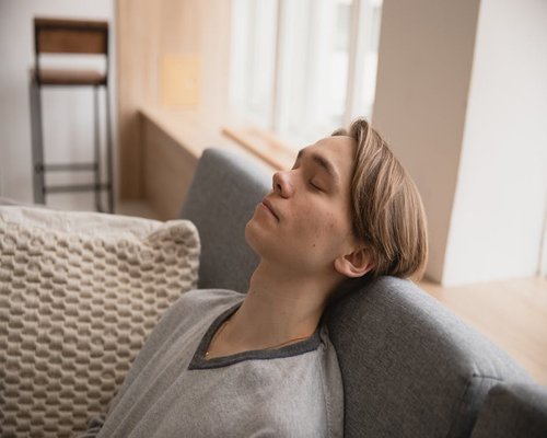 A person resting calmly on a sofa with natural light